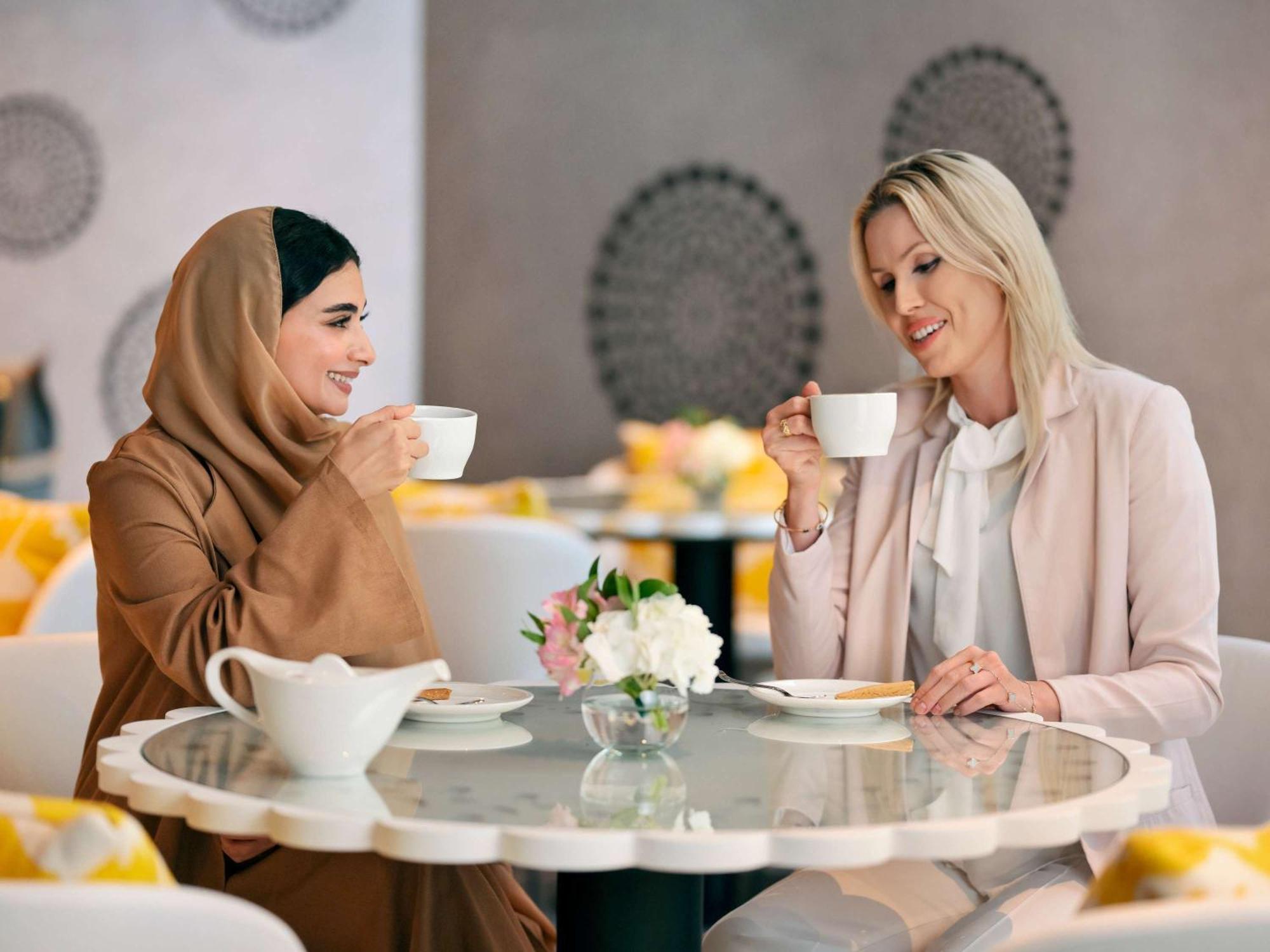 Moevenpick Hotel & Apartments Ghala Maskat Exterior foto Two women drinking coffee